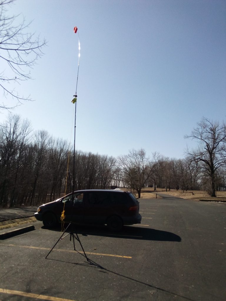 minivan in parking lot with buddipole antenna in foreground