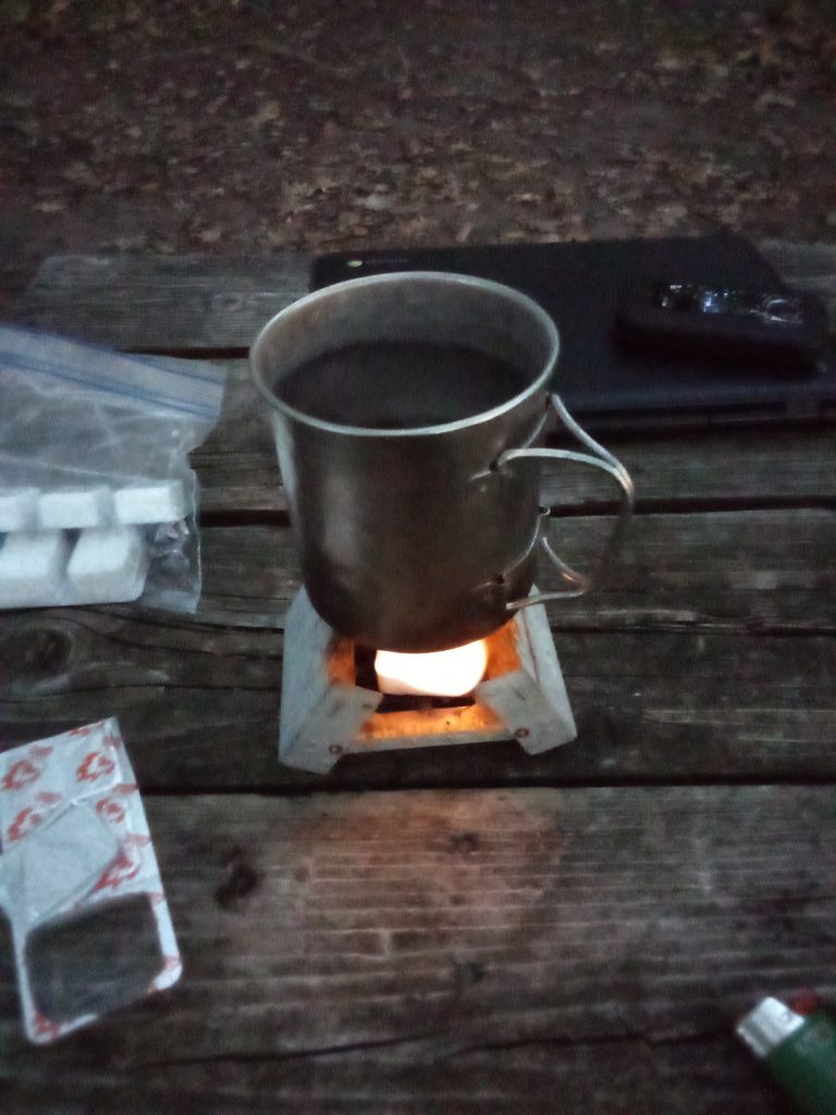 titanium cup full of water heating on a small camping stove